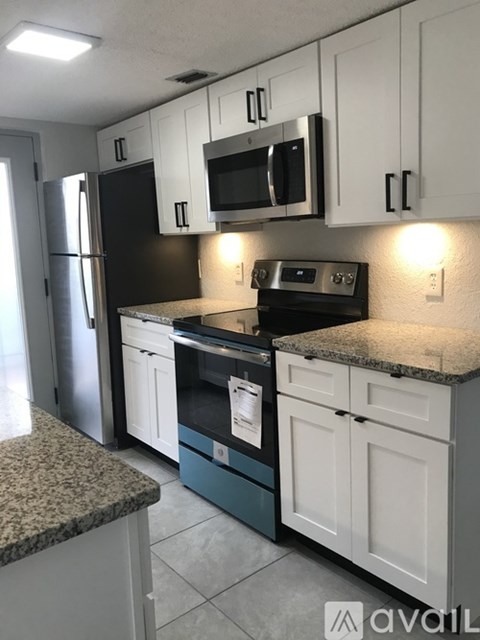 A kitchen with black and white cabinets and a granite countertop.
