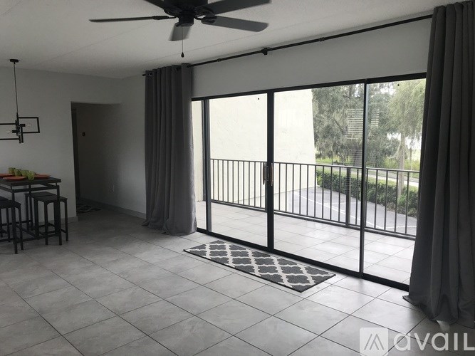 A spacious room with a ceiling fan and sliding glass doors leading to a balcony.