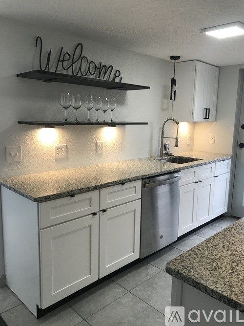 A kitchen with granite countertops and white cabinets.