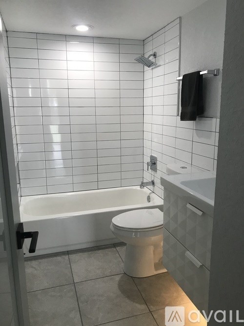 A white tiled bathroom with a toilet, sink, and bathtub.