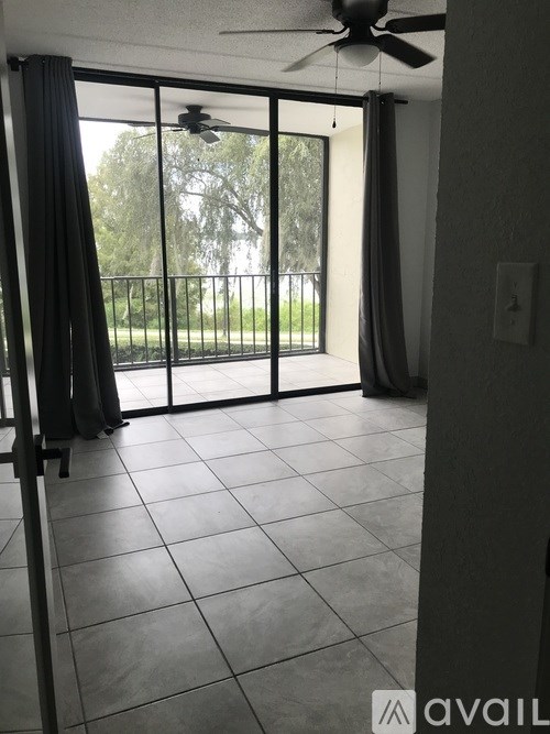A room with a ceiling fan and sliding glass doors leading to a balcony.