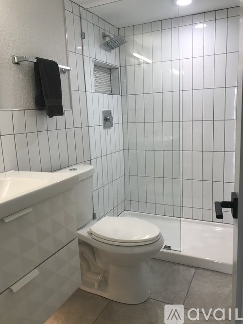 A white toilet in a bathroom with a black towel hanging on the wall.