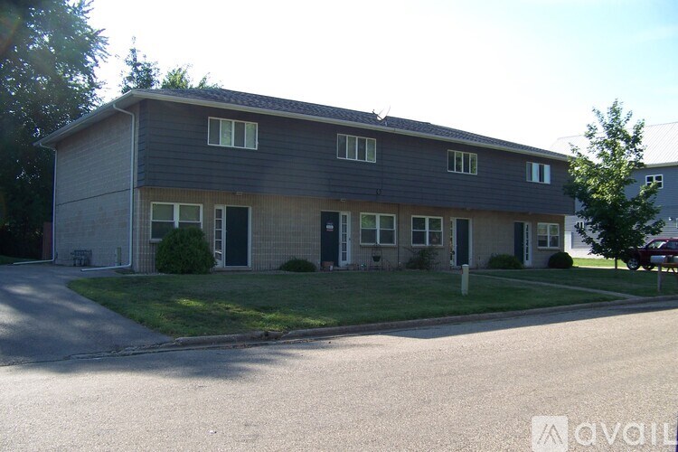 A two-story building with a grey roof and a parking lot in front.