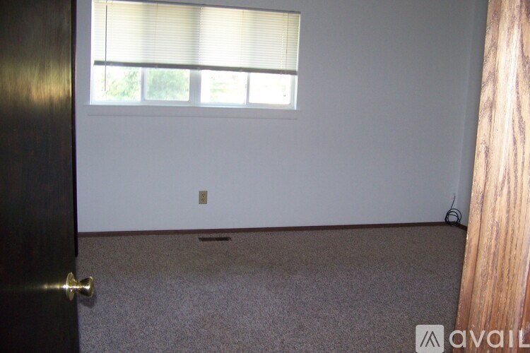 A room with a door, window, and carpeted floor.