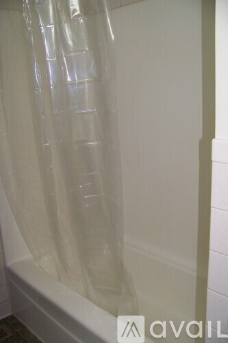 A white shower curtain hanging in a bathroom.