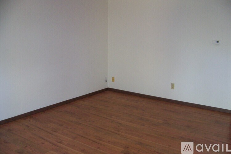A room with wooden flooring and white walls.