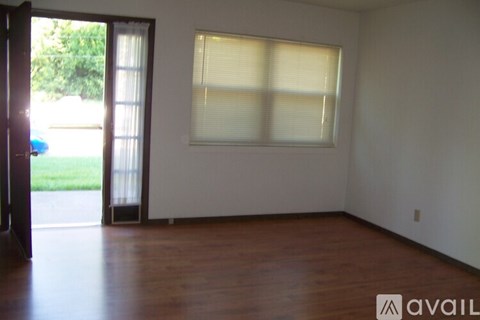 A room with a window and wooden floors is available for rent.