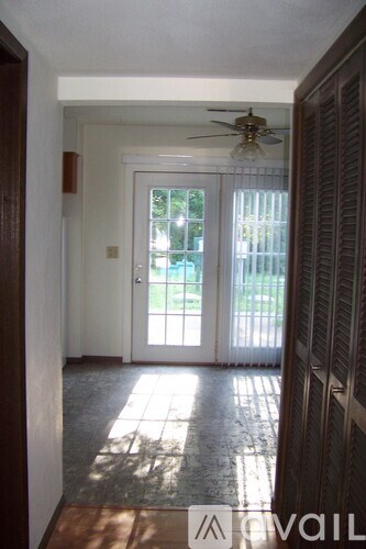 A hallway with a fan and a door leading outside.