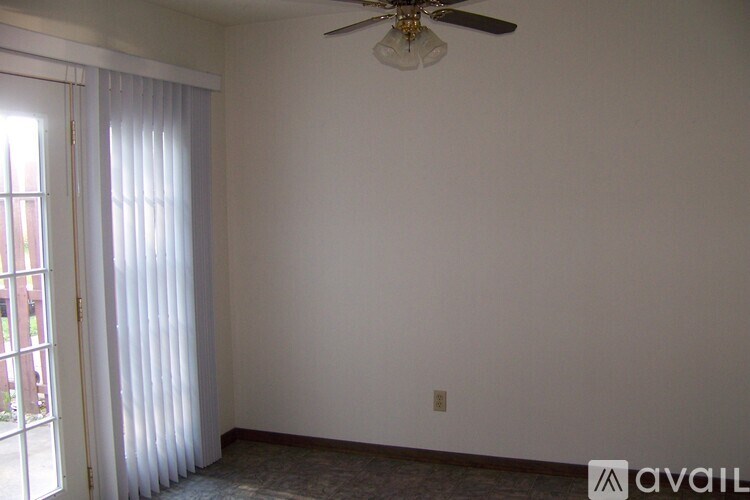 A room with a ceiling fan and a window with curtains.