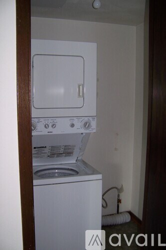 A small white washing machine sits in a narrow laundry room.