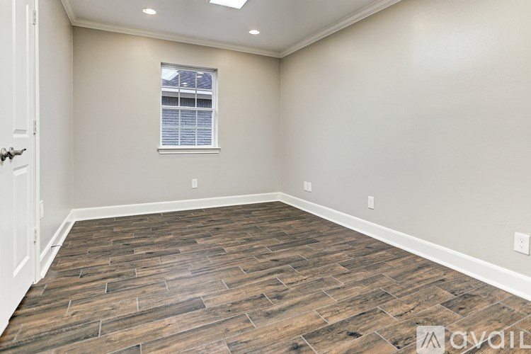 A room with wooden flooring and a window with blinds.