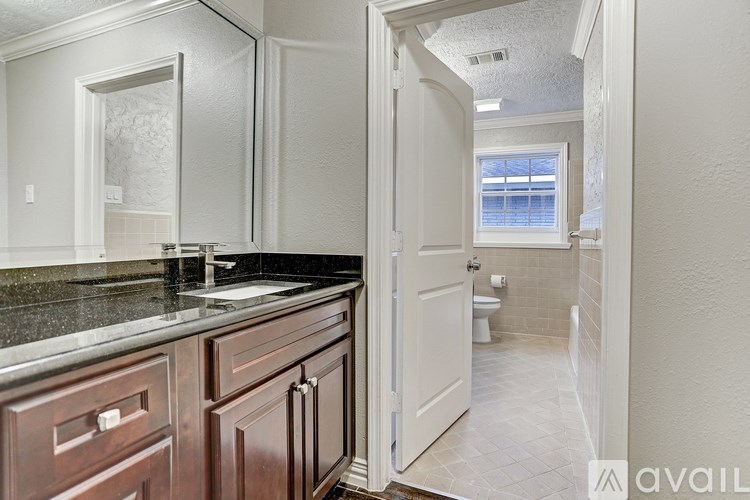 A bathroom with a sink, toilet, and a window.