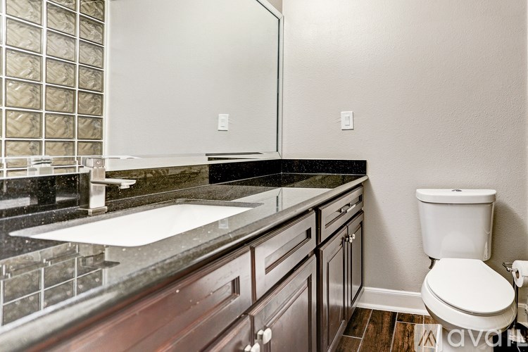 A bathroom with a toilet, sink, and mirror.