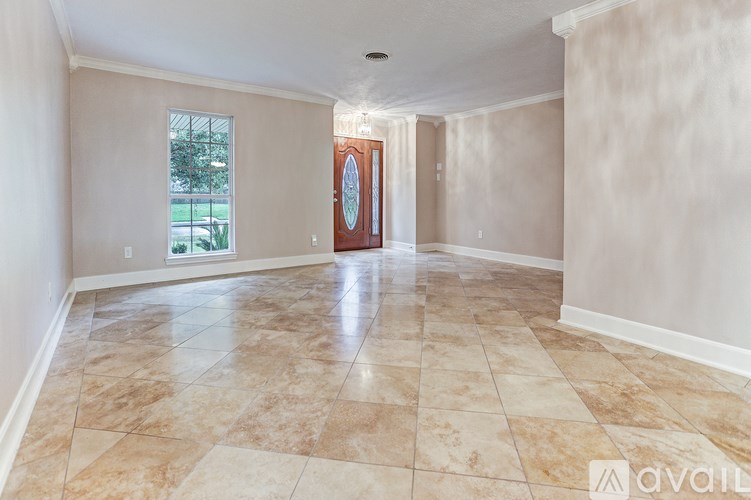A spacious room with tiled flooring and a doorway leading to another room.