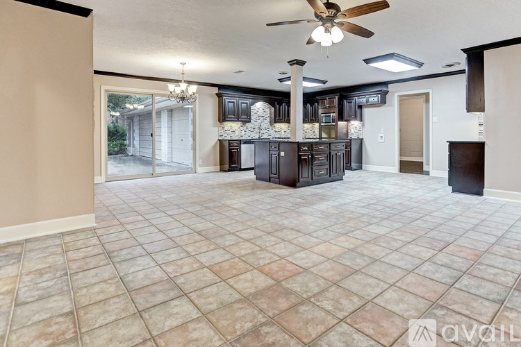 A spacious kitchen and dining area with tile flooring and a ceiling fan.