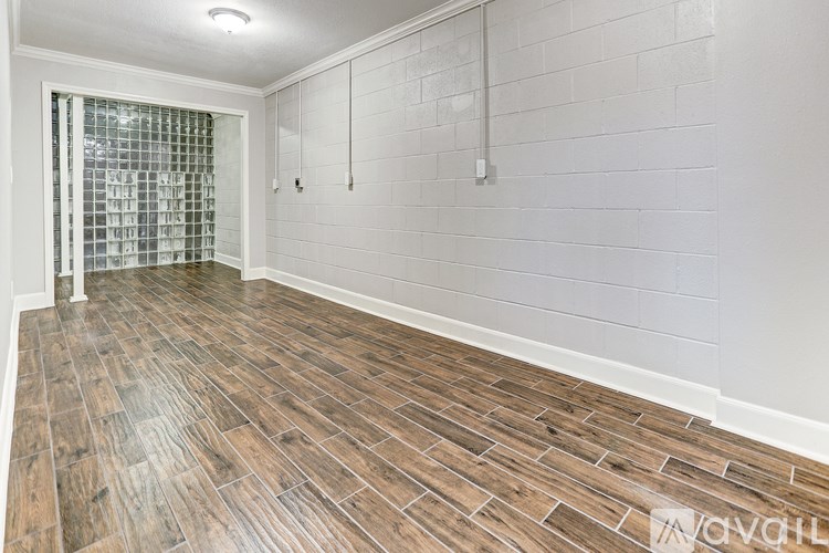 A room with wooden flooring and a glass block wall.