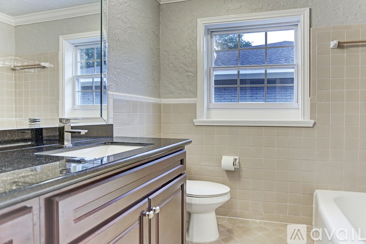 A bathroom with a toilet, sink, and window.