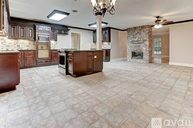 A spacious kitchen with a stone fireplace and a chandelier.