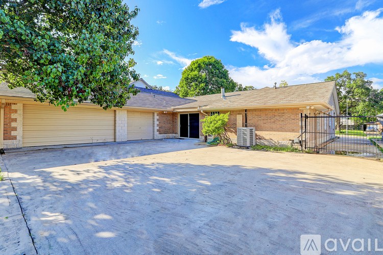 A house with a driveway and a tree in front of it.