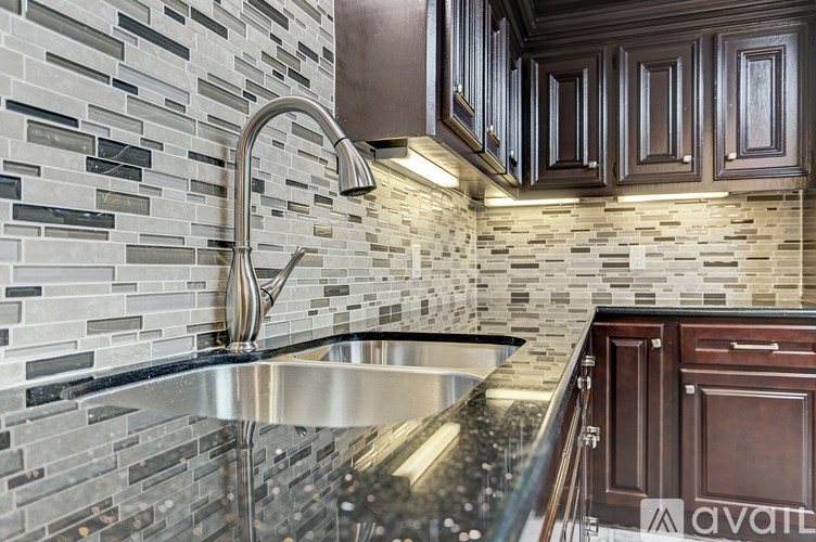 A kitchen with a sink and a wall of tiles.