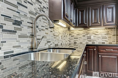 A kitchen with a sink and a wall of tiles.