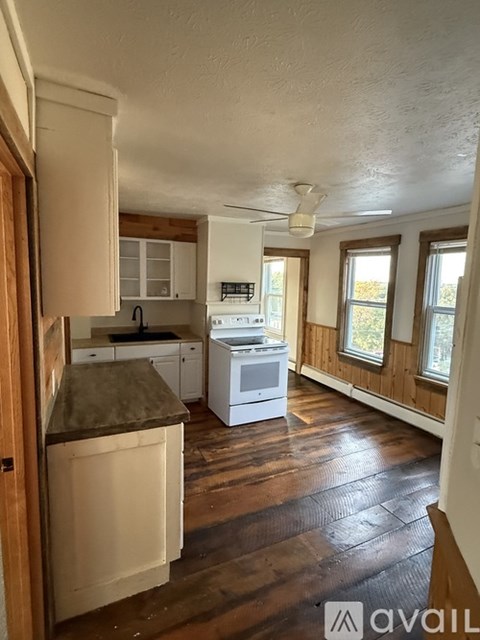 A kitchen with wooden cabinets and a white stove top oven.