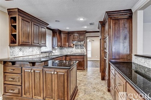 A kitchen with wooden cabinets and a black countertop.
