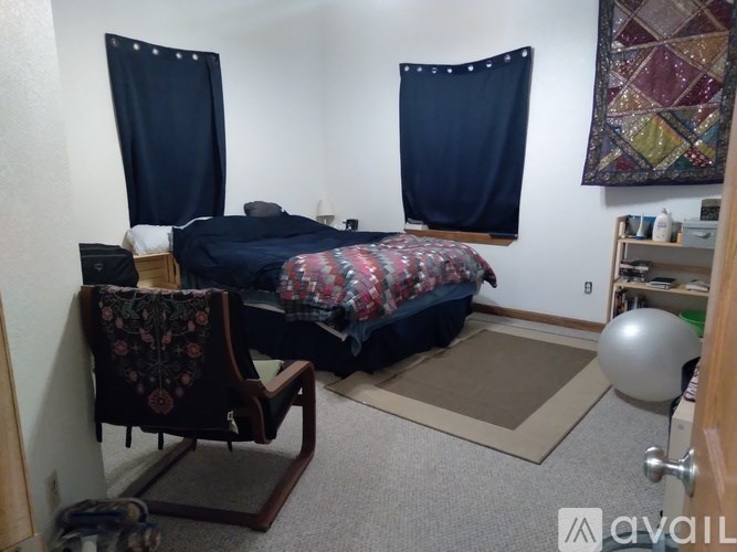 A bedroom with a bed, chair, and a ball.