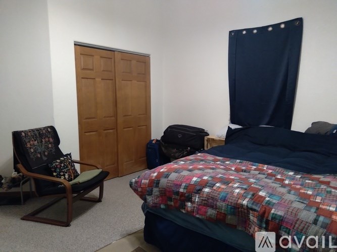 A bedroom with a bed, chair, and wardrobe.