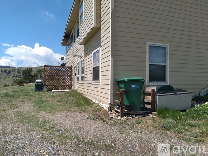 A house with a green trash bin and a white hot tub in front.