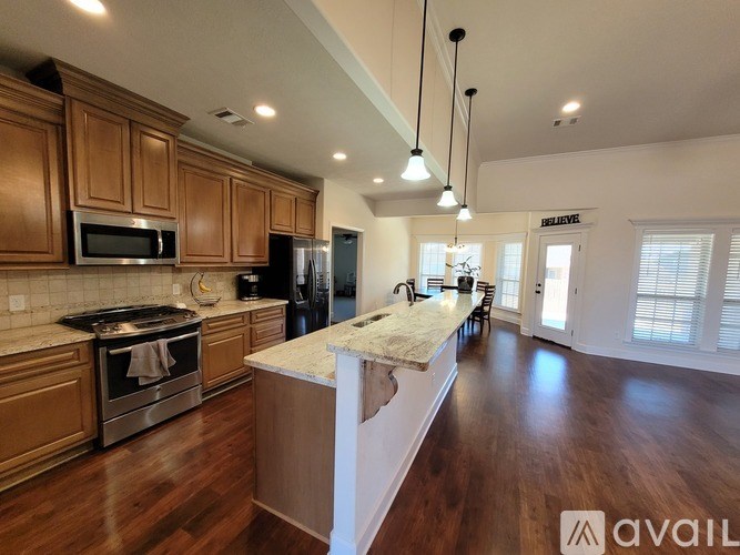 A kitchen with wooden cabinets and a marble island.