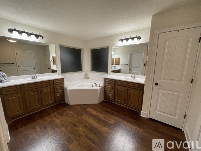 A bathroom with wooden floors and white walls.