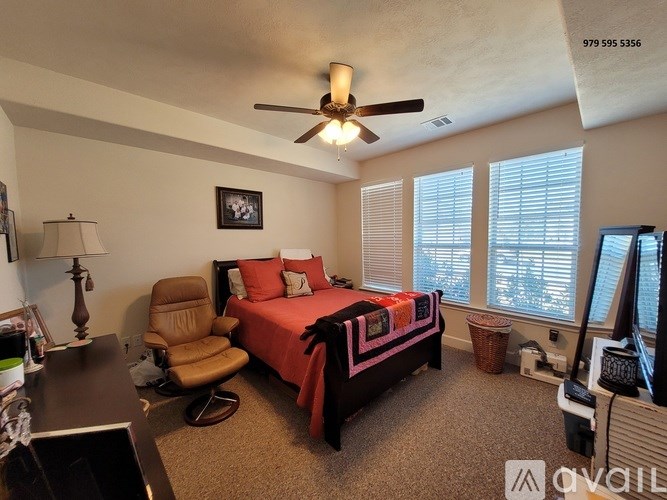 A bedroom with a bed, chair, and ceiling fan.