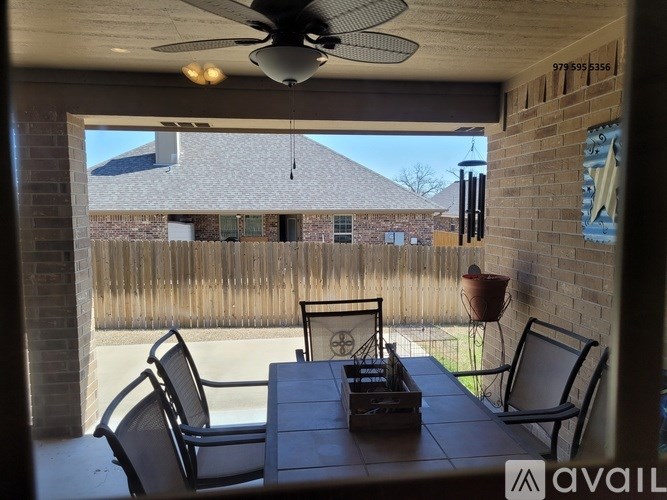 A patio with a table and chairs is shown with a house in the background.