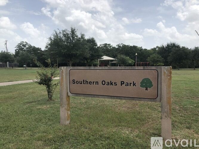 A sign for Southern Oaks Park stands in a grassy field.