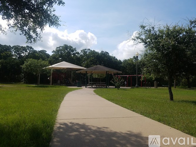 A park with a walkway, trees, and a pavilion.