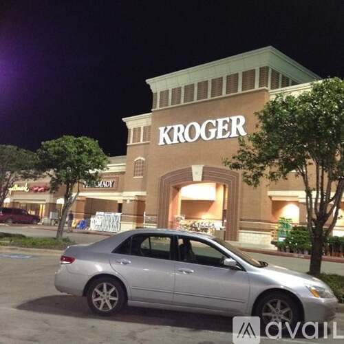 A silver car is parked in front of a Kroger store.