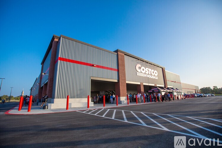 A Costco Wholesale store with a line of people waiting to enter.