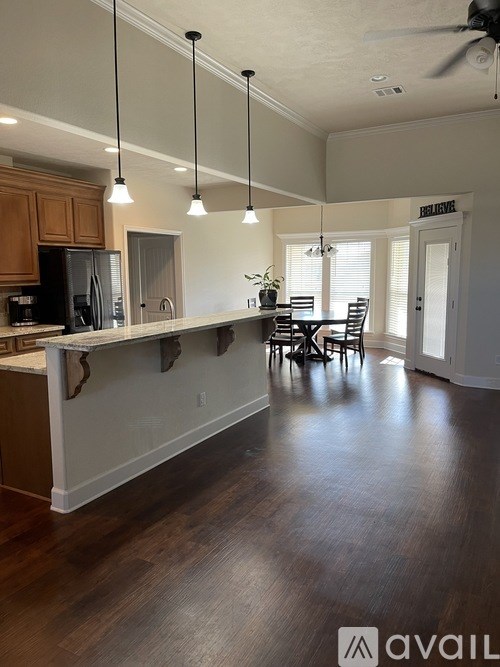 A kitchen with wooden cabinets and a countertop with a dining table and chairs.