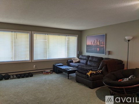 A living room with a black leather couch and a framed picture on the wall.