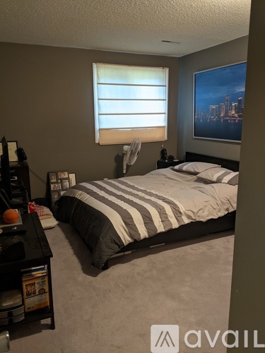A bedroom with a bed, nightstand, and window with blinds.