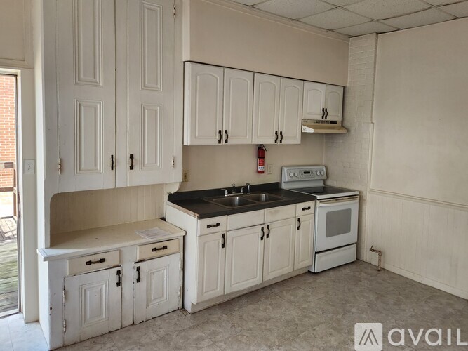 A kitchen with white cabinets and a black countertop.