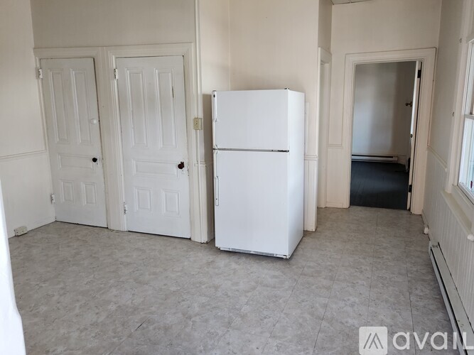 A white refrigerator in a room with two doors.