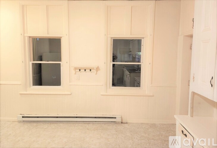 A room with two windows and a radiator on the floor.