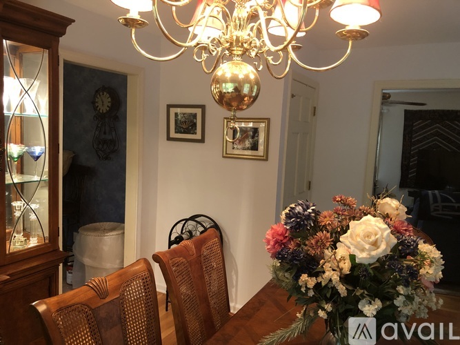 A dining room with a chandelier, two chairs, and a table with a vase of flowers.