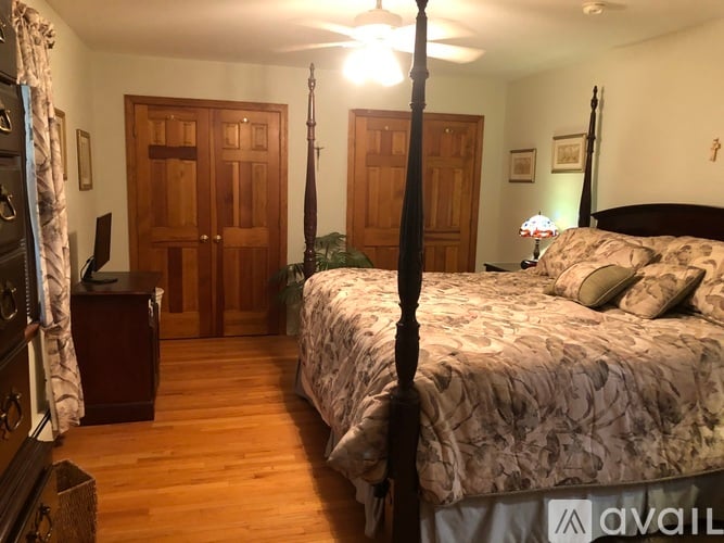 A bedroom with a four poster bed and a wooden floor.