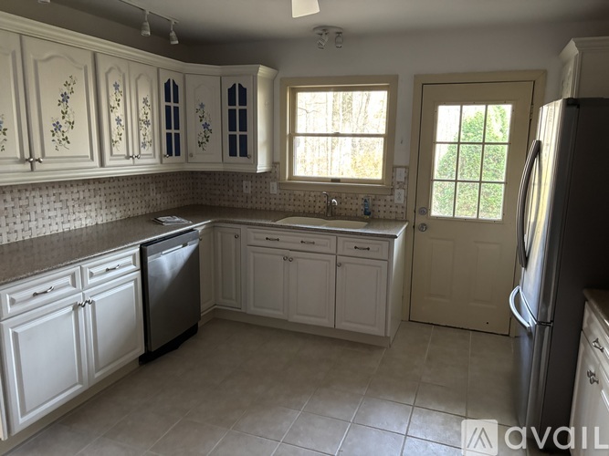 A kitchen with white cabinets and a black dishwasher.