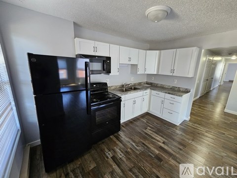 A black fridge and microwave in a kitchen with white cabinets.