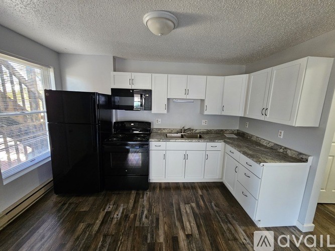 A kitchen with black appliances and white cabinets.