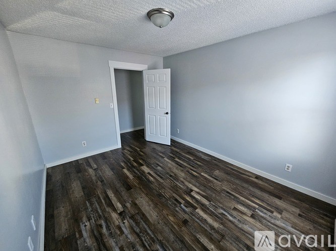 A room with wooden flooring and a white door.